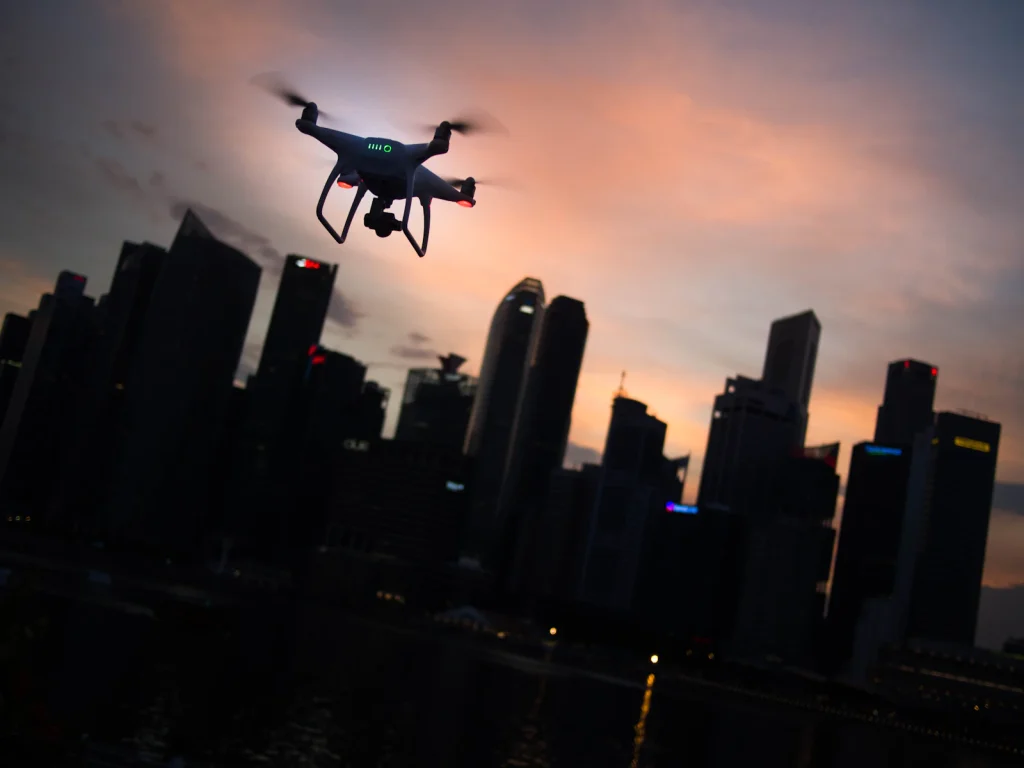 Surveillance drone silhouetted against a city skyline at dusk